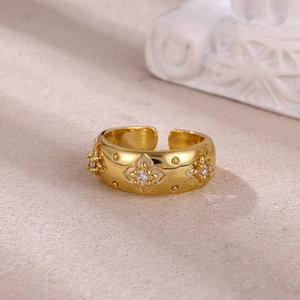Macro detail of gold plated ring with embossed floral patterns and clear zircon accents