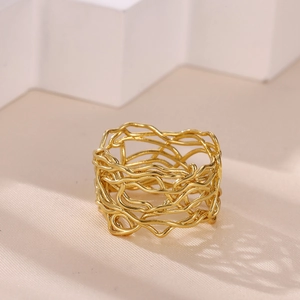 Macro detail of gold irregular hollow wire woven ring on a beige silk surface