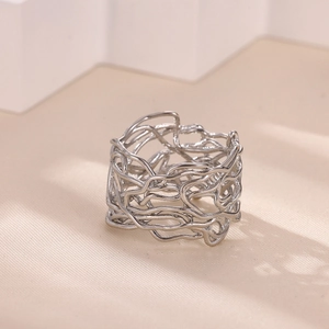 Detail view of silver hollow irregular wrap ring on minimalist beige textured surface
