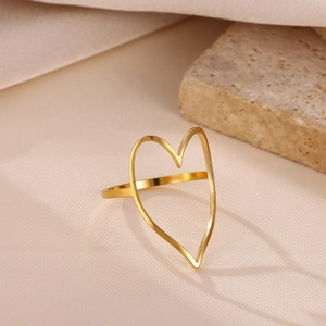 Detailed view of wide irregular gold heart ring on warm silk and stone background