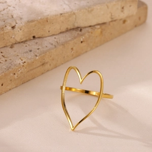 Detailed close-up of a large irregular hollow heart ring in gold finish on stone
