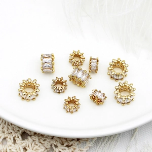 Detailed macro view of 18K gold plated charms with micro-set cubic zirconia on white feathers