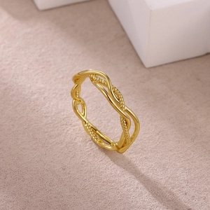 Detail view of gold stainless steel ring with elegant dual twisted cross band and bead texture