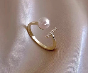 Macro detail of 18K gold bow ring with white pearl and micro-pave zircons on silk