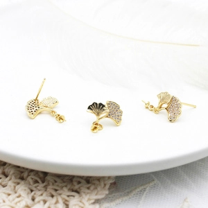 Detalle de pendientes de hoja de ginkgo chapados en oro 18K con esmalte negro y circonitas