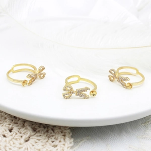 Detailed view of 18K gold plated bow scissors ring bases with sparkling cubic zirconia