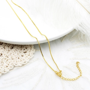 Detail van 18K vergulde ketting met karabijnsluiting op een elegante witte achtergrond
