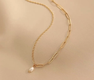 Dettaglio catena a graffetta placcata oro 18K con elegante ciondolo in perla bianca