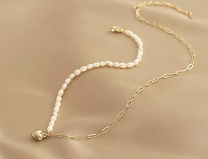 Dettaglio della collana asimmetrica placcata oro 18K con perle e ciondolo a cuore
