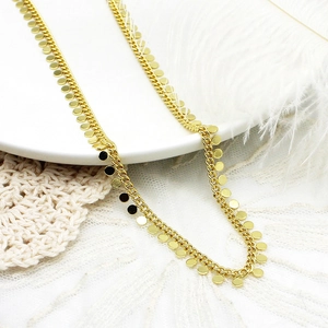 Detail van 18K vergulde gourmetketting met kleine ronde schijfbedeltjes op een wit bord