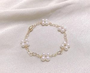 Dettaglio del bracciale di perle placcato oro 18K su fondo in tessuto di seta bianca