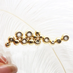Orecchino moderno placcato oro 18 carati con sfere metalliche su sfondo piuma bianca