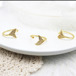 Makro-Detail von 18K vergoldeten Fischschwanz-Ringen mit Zirkonia-Besatz auf Tablett