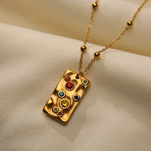 Detailed close-up of 18K gold-plated rectangle pendant with colorful gemstones on silk