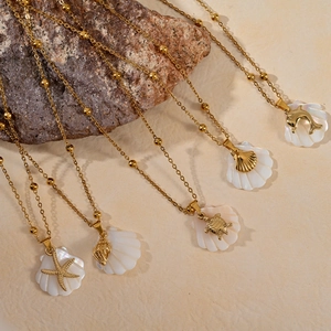 Detalle de dijes de estrella de mar y tortuga en collares de nácar y cuentas doradas