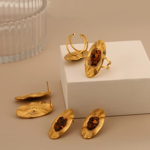 Detail of vintage gold oval earrings and ring set with brown natural stone inlay