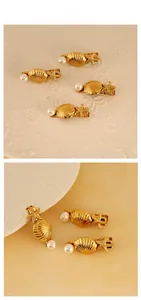 Nahaufnahme goldener Muschel- und Seestern-Haarklammern mit Perlendetail auf weißem Teller