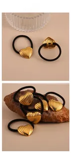 Detail showing golden heart-shaped metal charms on elastic black hair ties with textured finish