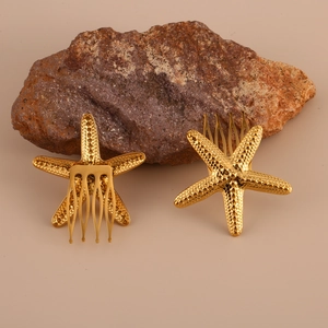 Pair of gold starfish metal hair combs with textured finish on elegant beige background