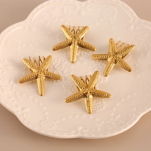 Set of four gold starfish hair clips with textured finish on white ceramic plate