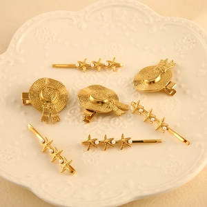 Golden straw hat and starfish hair clips set with white pearls on a ceramic plate