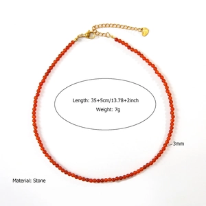 Detail showing 3mm orange-red natural stone beads with golden lobster clasp and heart tag