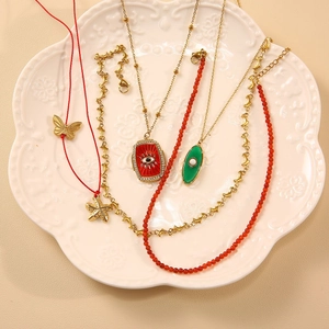 Golden multi-layer jewelry set featuring starfish, evil eye pendants and red beads