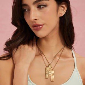 Three-layer gold zodiac necklace set with rectangular embossed pendants on a model