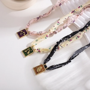 Close-up of handmade floral silk scarf necklaces with gold zodiac enamel pendants