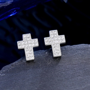 Macro shot of silver cross stud earrings with sparkling cubic zirconia on a stone base