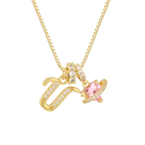 Detail of gold necklace featuring zircon letter U and pink heart-shaped planet pendant
