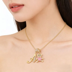 Gold teddy bear necklace with letter A pendant and pink heart stone on a fine chain
