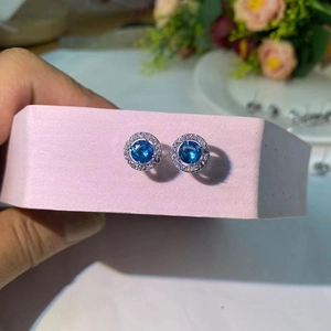 Vue détaillée de boucles d'oreilles rondes en argent avec pierre bleue et halo de zircons