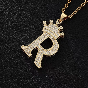 Detailed macro view of gold-plated crown letter R pendant necklace with pavé cubic zirconia