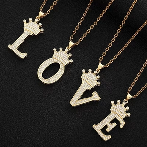 Detailed view of LOVE letter pendants with gold crowns and sparkling white zircons