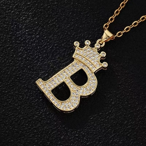 Close-up of gold crown letter B pendant with sparkling zircons on black leather