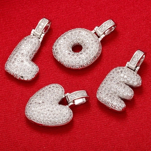 Detailed macro view of silver LOVE letter pendants with micro-pave cubic zirconia on red fabric