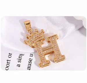 Macro detail of gold crown H letter pendant with pave set cubic zirconia stones