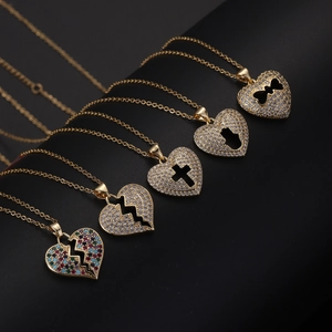 Dettaglio di cinque ciondoli a cuore placcati oro 18K con inserti in zirconi Hamsa e croce