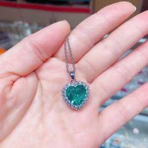 Detail eines herzförmigen smaragdgrünen Zirkonia-Anhängers mit Kristallen auf silberner Kette