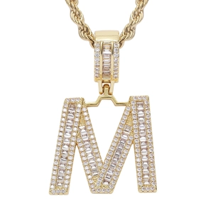 Macro detail of iced-out letter M pendant with cubic zirconia on gold rope chain