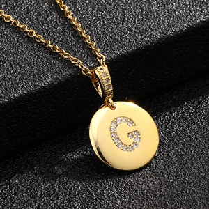 Detalle del collar con letra G dorada y micropavé de circonitas sobre soporte de cuero