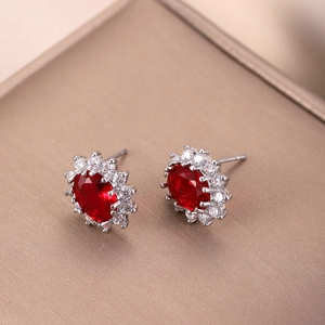 Detalle de pendientes de rubí con halo de circonitas en montura de metal plateado