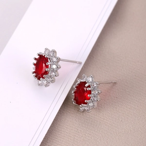 Elegantes pendientes reales con rubí óvalo y halo de circonitas en diseño de flor retro
