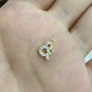 Détail d'un pendentif lettre dorée avec oxydes de zirconium blancs sur une main