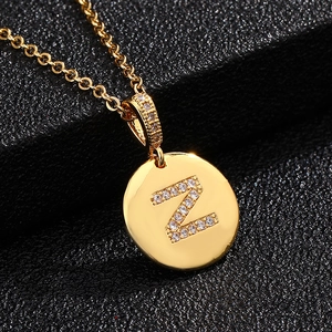 Detalle macro del colgante redondo dorado con letra Z de circón en cadena fina