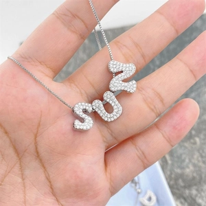 Detailed shot of SUN letter pendant with zircons held in hand for size scale