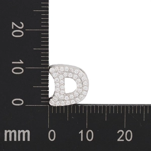 Macro shot of 12mm x 15mm silver letter D pendant with cubic zirconia and a ruler