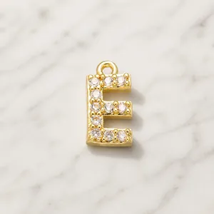 Macro shot of gold-plated letter E pendant with clear cubic zirconia stones
