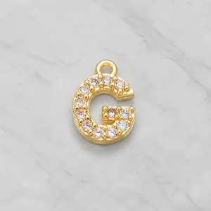 Macro shot of gold plated letter G pendant inlaid with sparkling cubic zirconia stones